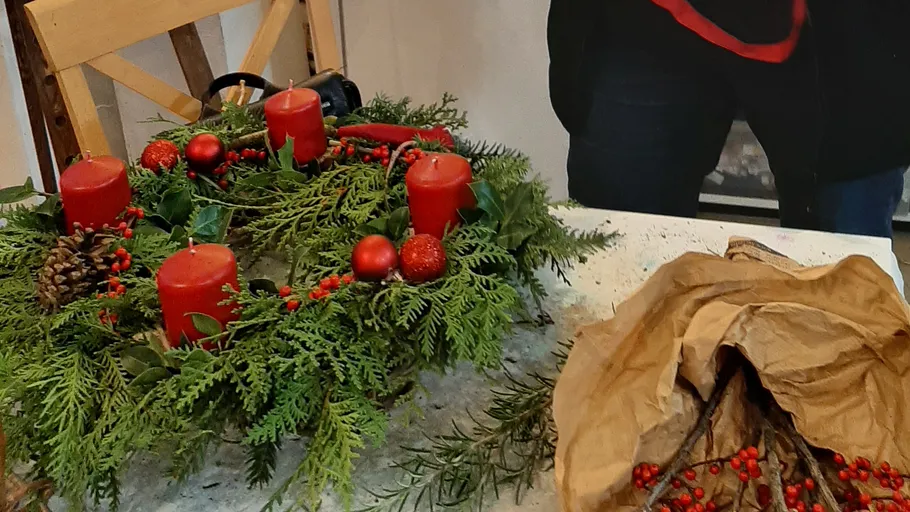 Festive wreath with red candles on table.