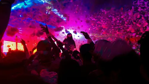 Menschenmenge genießt Schaumparty mit bunten Lichtern.