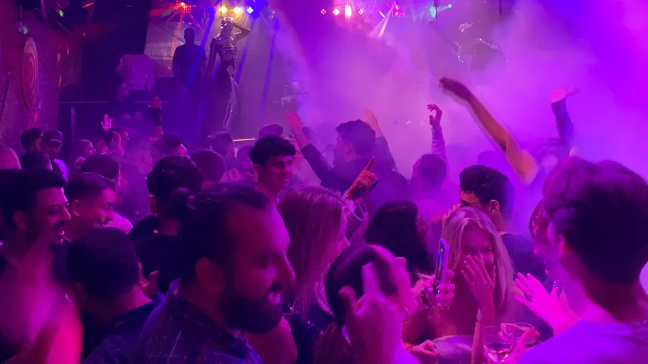 Crowded nightclub dance floor with colorful lights.