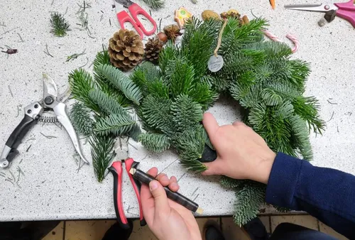 Person making a wreath on a table.