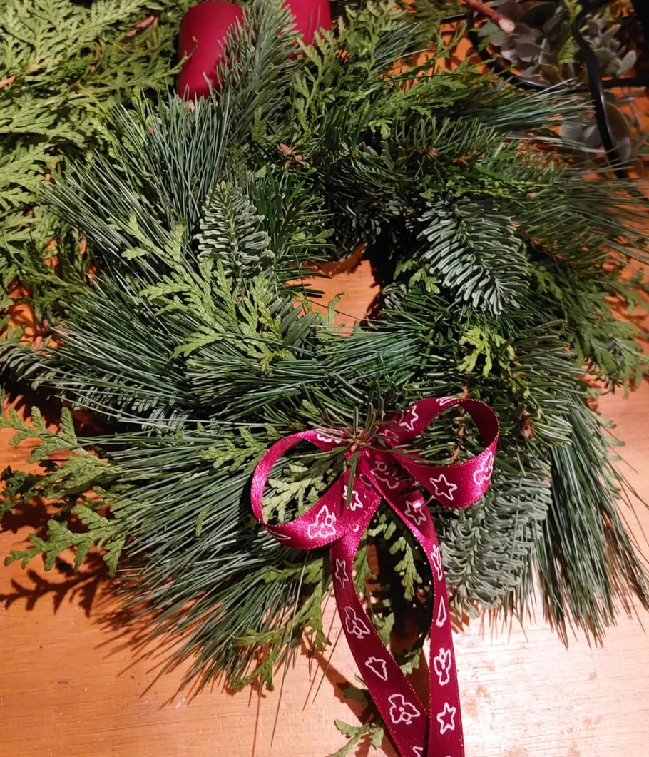 Festive wreath on wooden table with ribbon.