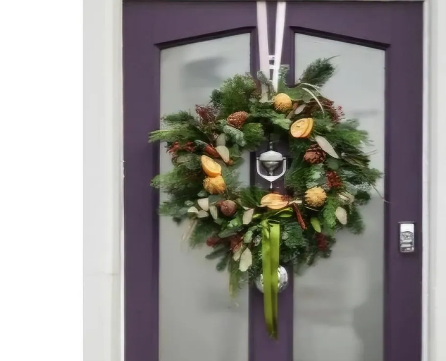 Festive wreath hanging on purple door.