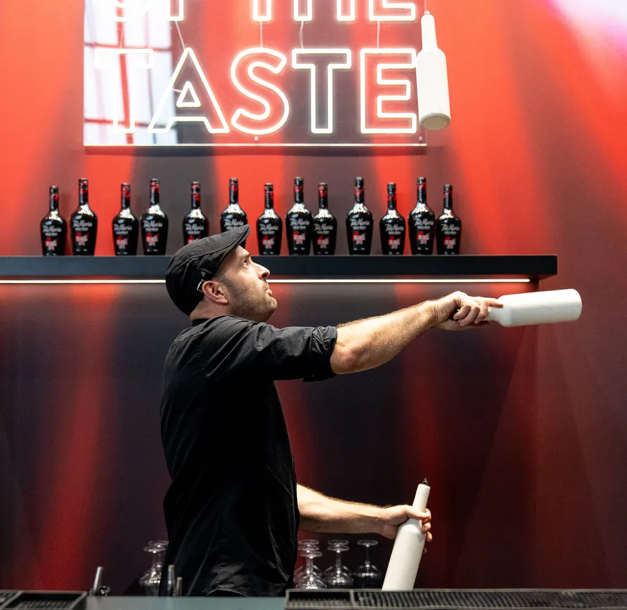 Bartender juggling bottles in front of shelves.