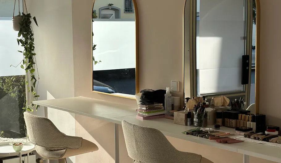 Schminktisch mit Spiegeln und Stühlen.