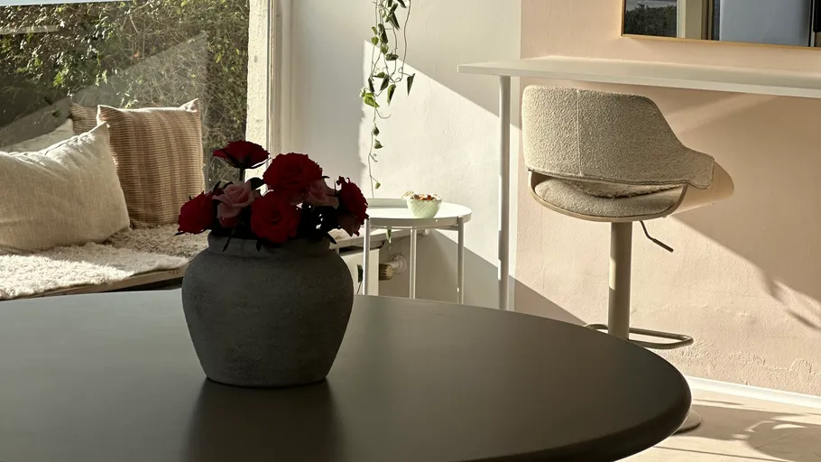 Vase mit Blumen auf Tisch, sonniger Raum.