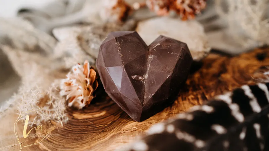 Chocolate heart on wooden surface, autumn decor.