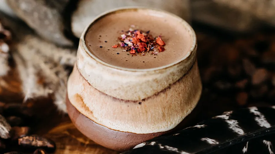 Ceramic cup with cacao beverage and garnish.