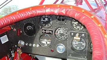 Flugzeugcockpit mit Instrumenten und roter Polsterung.