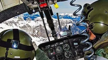 Piloten fliegen Hubschrauber über schneebedeckte Berge.