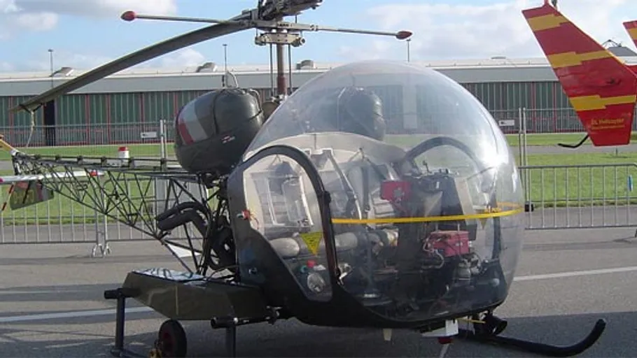 Vintage helicopter displayed on tarmac.