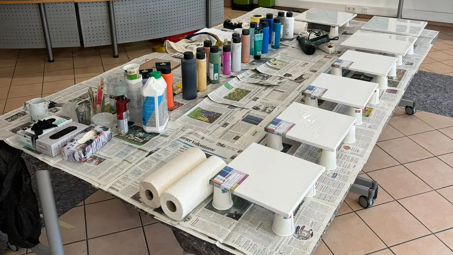 Art supplies on table with newspaper covering.