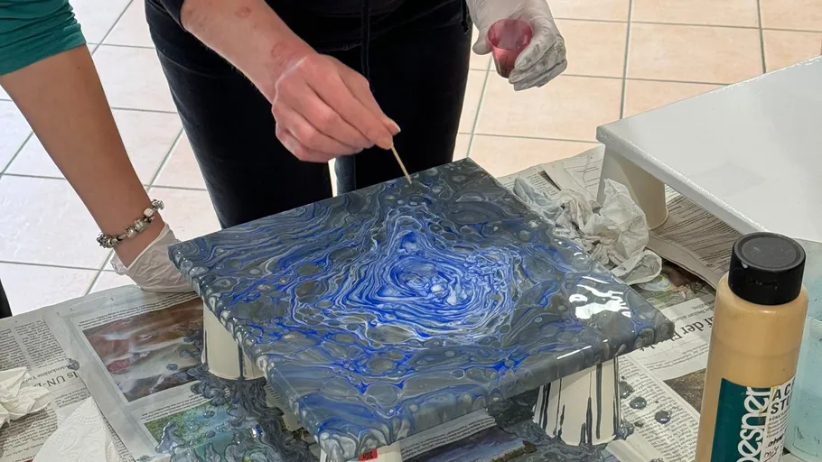 Person creates acrylic pour art on canvas.