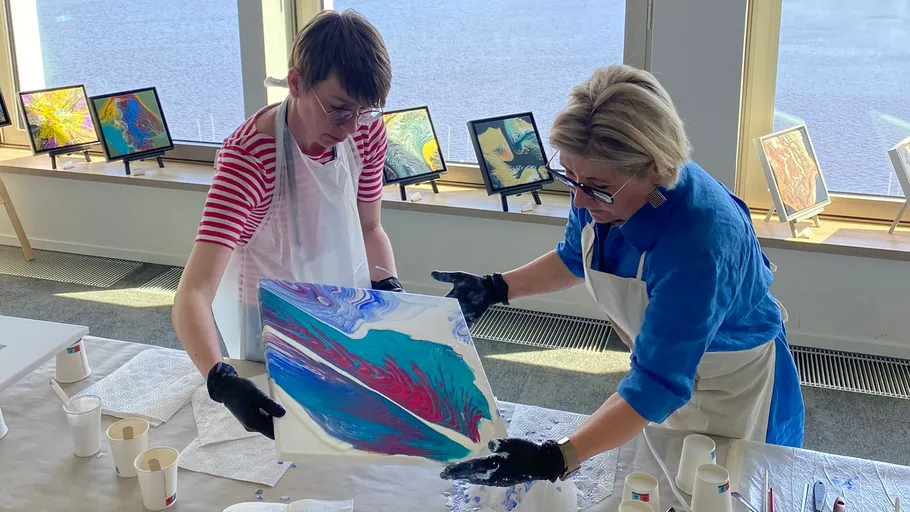 Two people painting in a bright room.
