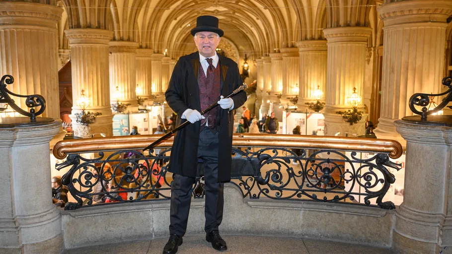 Man in vintage attire stands in ornate hall.