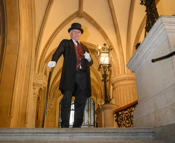 Man in formal attire descending staircase indoors.