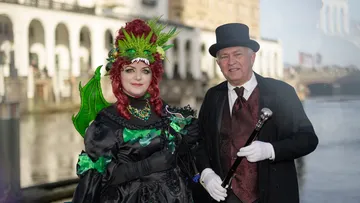 Two people in costumes by a riverside.