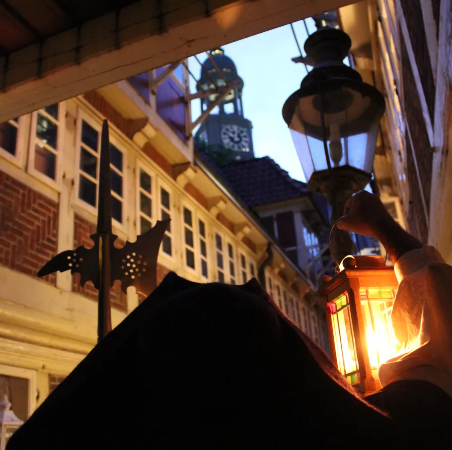 Person holding lantern near clock tower.