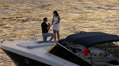 Mann macht Frau auf Boot bei Sonnenuntergang Antrag.