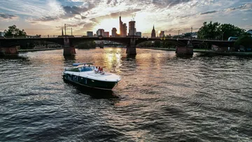 Boat cruising on a river at sunset.