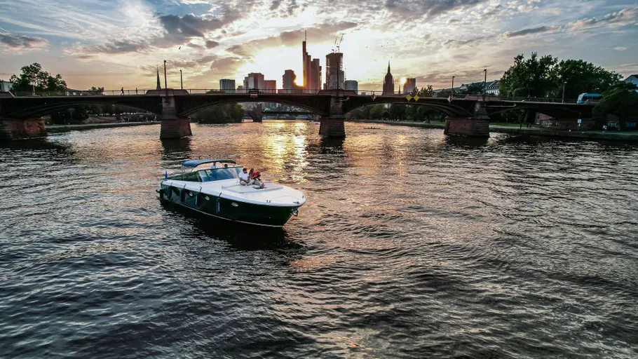 Boot fährt bei Sonnenuntergang auf einem Fluss.