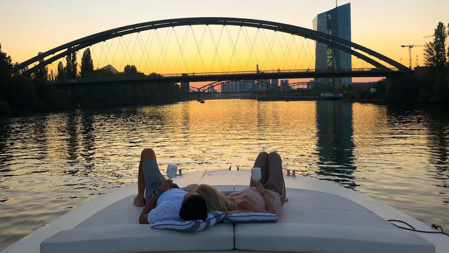 Zwei Personen entspannen auf Boot bei Sonnenuntergang.