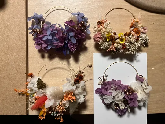 Vier Blumenkränze auf einem Holztisch.