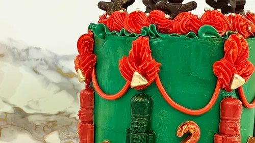 Grüner Kuchen mit roten Verzierungen und Figuren.