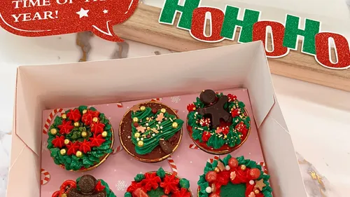 Box of festive cupcakes with Christmas decorations.