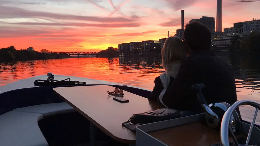Paar auf Boot beobachtet Sonnenuntergang über Fluss.
