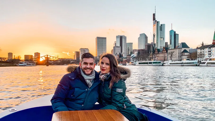 Paar sitzt im Boot bei Sonnenuntergang, Stadtsilhouette.