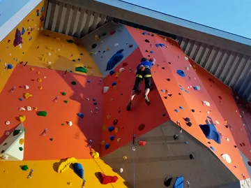 Person klettert bunte Indoor-Kletterwand.