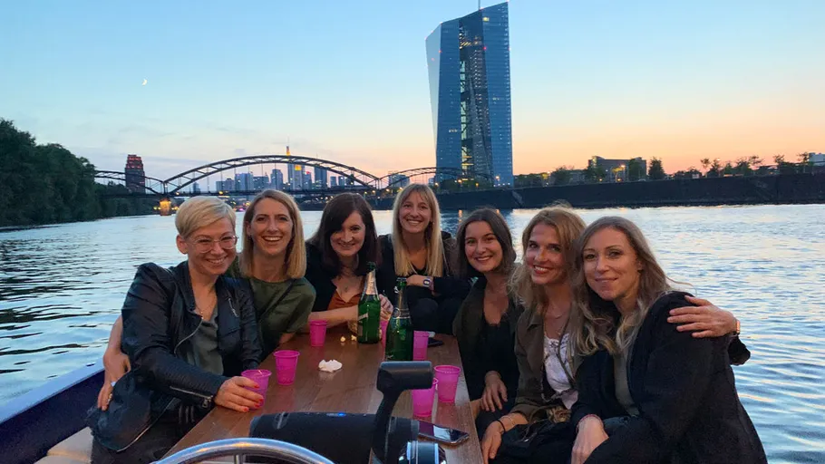 Eight people smiling on a boat at sunset.