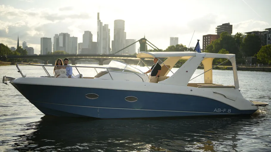 Boat with people on city river at sunset.