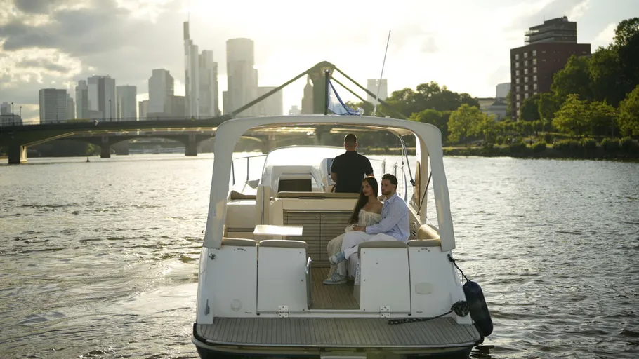 Yacht fährt auf Fluss, Stadtansicht im Hintergrund.