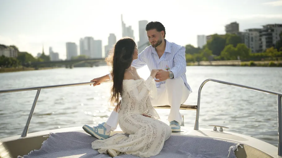 Couple sitting on boat in urban river setting.
