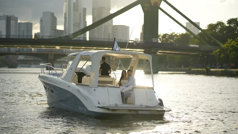 Motorboat with people cruising near city bridge.