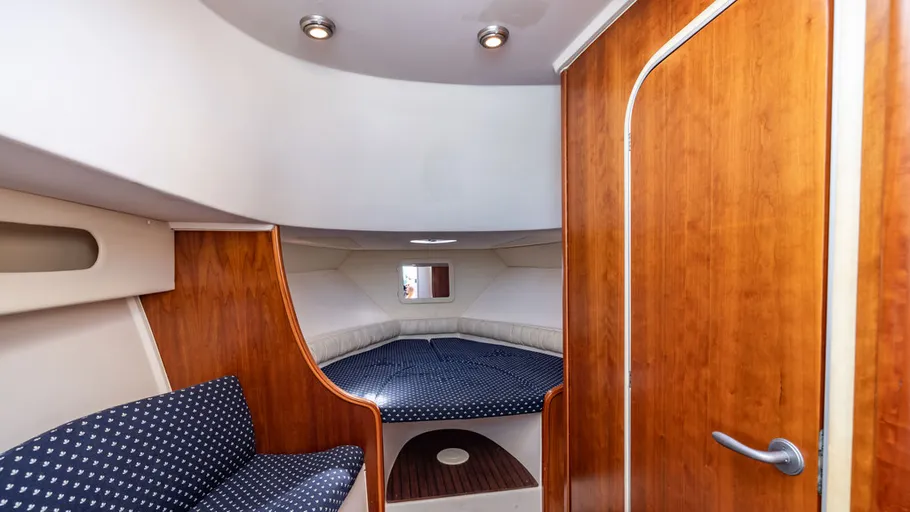 Kabineninnenraum mit rundem Bett und Sitzgelegenheit.