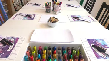 Art supplies arranged on a classroom table.