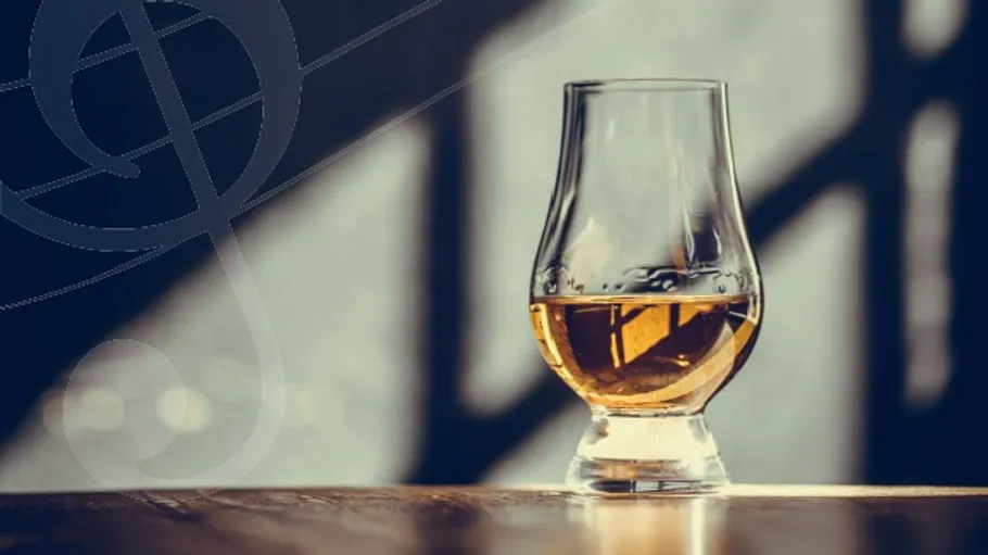 Whiskyglas auf Holztisch, schattiger Hintergrund.