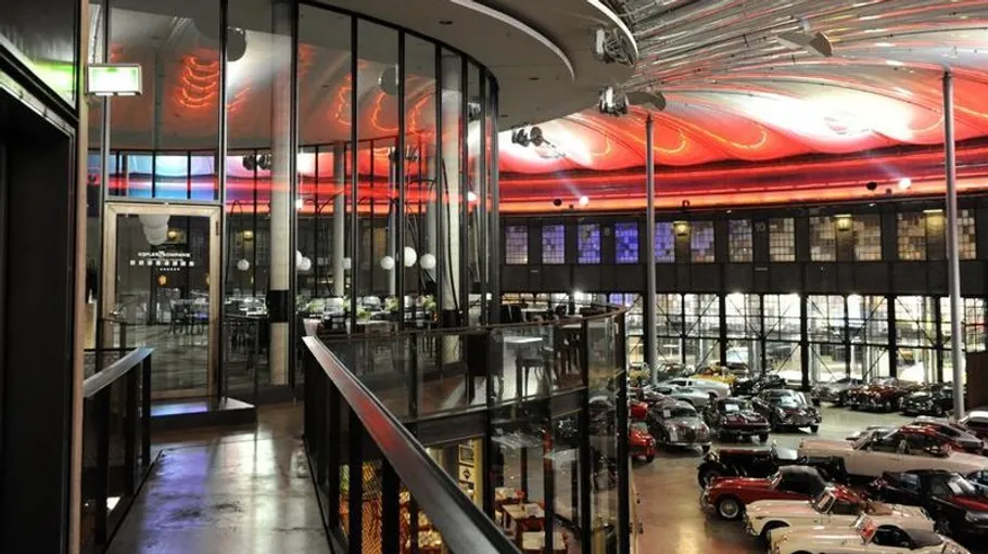 Spacious car showroom with vintage cars displayed.