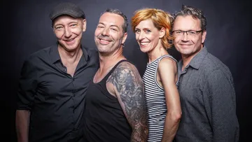 Four smiling people in a studio setting.