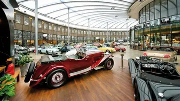 Classic cars displayed in a glass showroom.