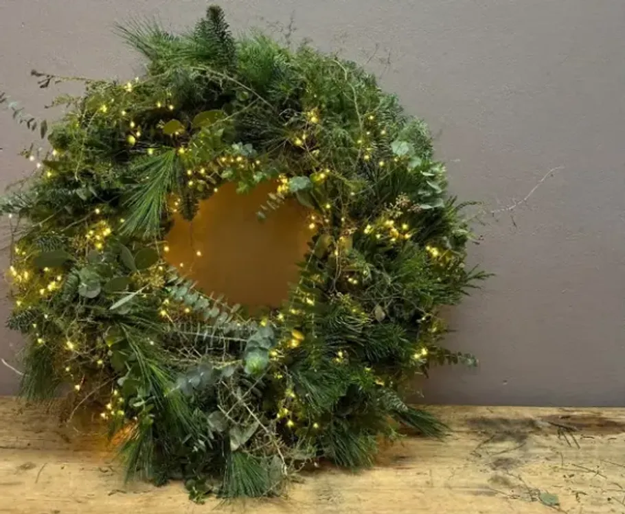 Green wreath with lights on wooden surface.