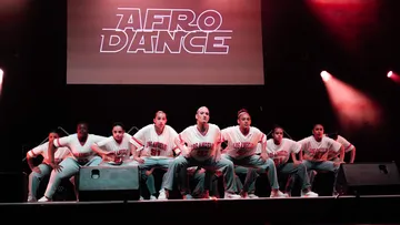 Gruppe Tänzer auf Bühne unter Afro Dance Schild.