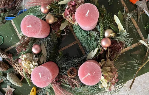Pink candles on decorative wreath, table surface.