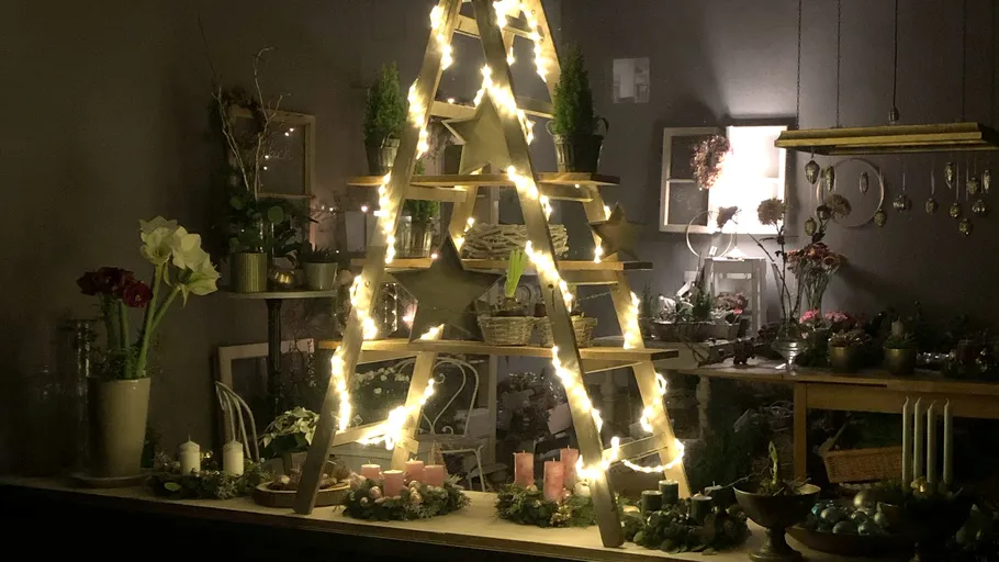 Wooden ladder decorated with lights, candles, plants.