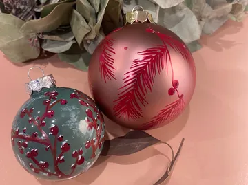 Zwei Christbaumkugeln mit Blattmustern.