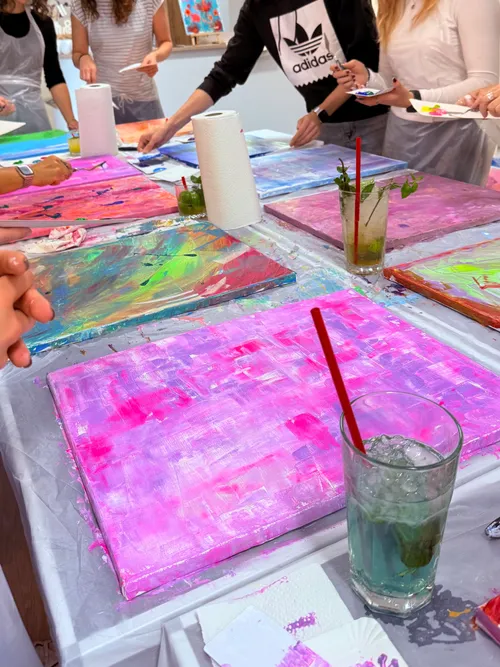 People painting colorful canvases in art class.