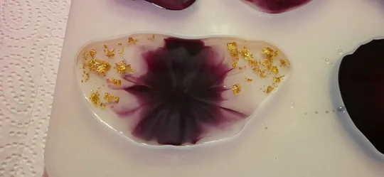 Resin art with gold flakes on white cloth.