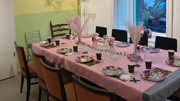 Esszimmertisch für eine Feier dekoriert mit Stühlen.